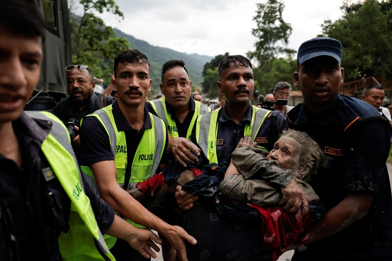 Warga berdiri di dekat rumah-rumah yang tertutup lumpur dan sebuah jalan setelah banjir bandang di Trishuli, Distrik Nuwakot, Nepal, pada 26 Agustus 2026. (REUTERS/Navesh Chitrakar)