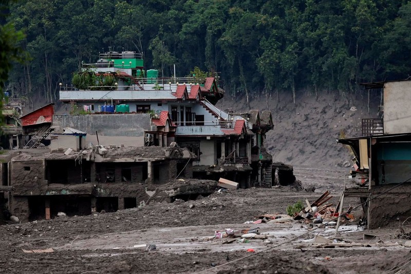 Warga berdiri di dekat rumah-rumah yang tertutup lumpur dan sebuah jalan setelah banjir bandang di Trishuli, Distrik Nuwakot, Nepal, pada 26 Agustus 2026. (REUTERS/Navesh Chitrakar)