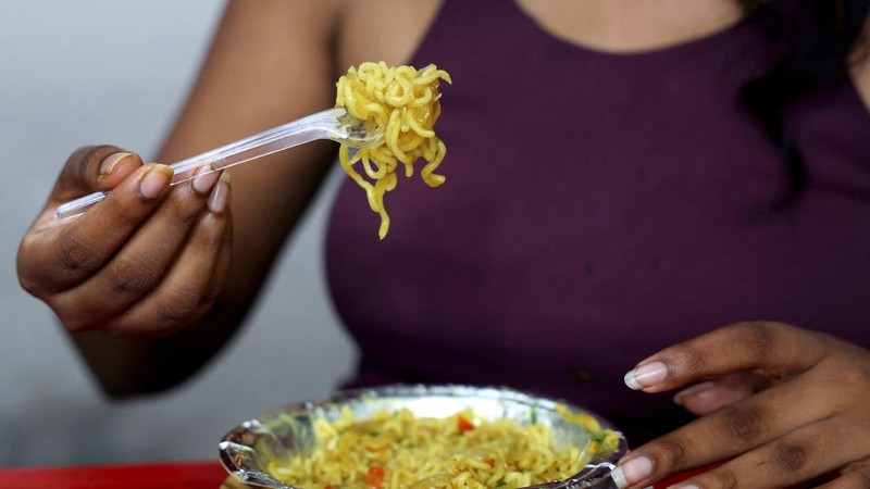 Seorang wanita menyantap mi instan Nestle Maggi 2-Minute di sebuah kedai makanan kaki lima di New Delhi, India, pada 13 Agustus 2026.