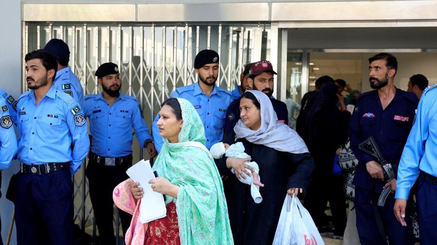 Seorang wanita yang menggendong bayi melintas di dekat petugas kepolisian saat meninggalkan bangsal usai kebakaran maut di rumah sakit Pakistan Institute of Medical Sciences (PIMS) di Islamabad, Pakistan, pada 26 Agustus 2026.