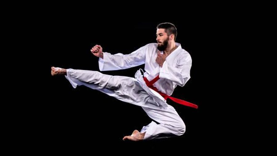 Ilustrasi praktisi karate pria sedang melayang di udara saat melakukan tendangan melompat. (Istock)