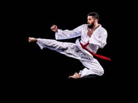Ilustrasi praktisi karate pria sedang melayang di udara saat melakukan tendangan melompat. (Istock)