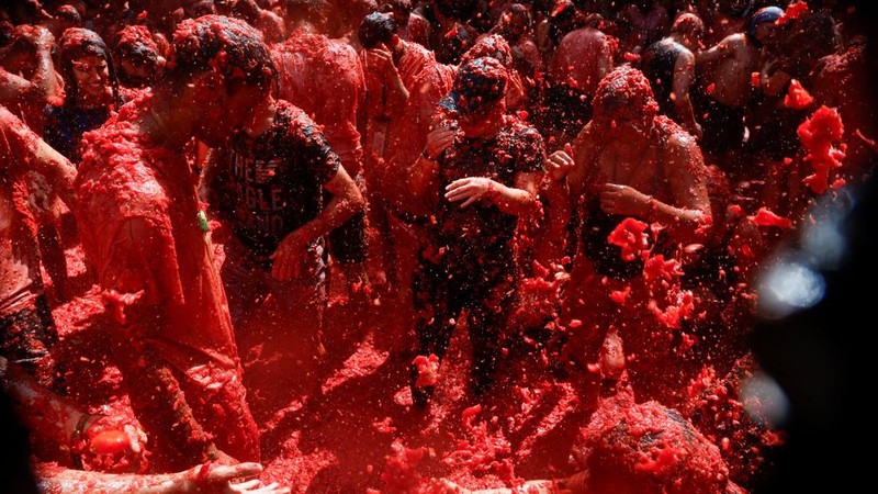 Para peserta bersenang-senang di tengah bubur tomat dalam festival perang makanan tahunan "La Tomatina" di Bunol, Spanyol, pada 26 Agustus 2026. (REUTERS/Thomas Peter)