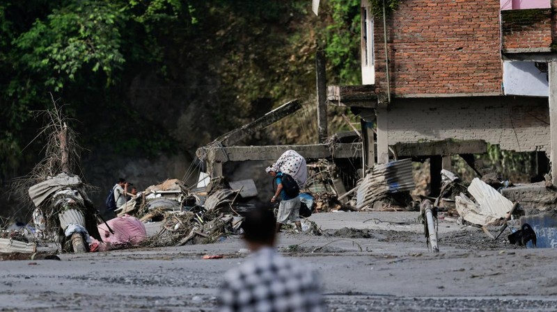 Seorang pria yang membawa barang-barangnya berjalan melintasi puing-puing pascabanjir dahsyat di Trishuli, Distrik Nuwakot, Nepal, pada 27 Agustus 2026.