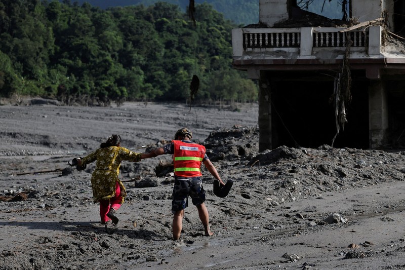 Warga melihat foto-foto korban tewas akibat banjir dan tanah longsor yang ditempel di gerbang untuk keperluan identifikasi di luar kamar jenazah di Kathmandu, Nepal, pada 27 Agustus 2026. (REUTERS/Sabrina Dangol)