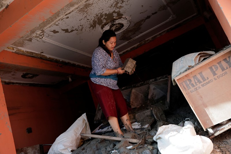 Warga melihat foto-foto korban tewas akibat banjir dan tanah longsor yang ditempel di gerbang untuk keperluan identifikasi di luar kamar jenazah di Kathmandu, Nepal, pada 27 Agustus 2026. (REUTERS/Sabrina Dangol)