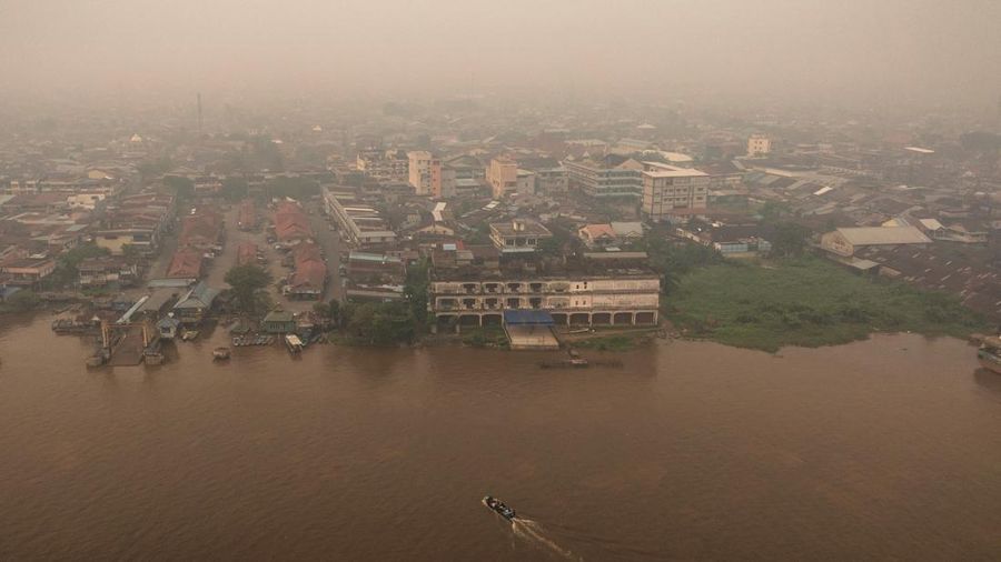 Tampilan dari drone memperlihatkan orang-orang menaiki perahu kayu menyeberangi Sungai Kapuas saat kabut asap akibat kebakaran hutan menyelimuti wilayah tersebut di Pontianak, Provinsi Kalimantan Barat, Indonesia, pada 27 Agustus 2026.