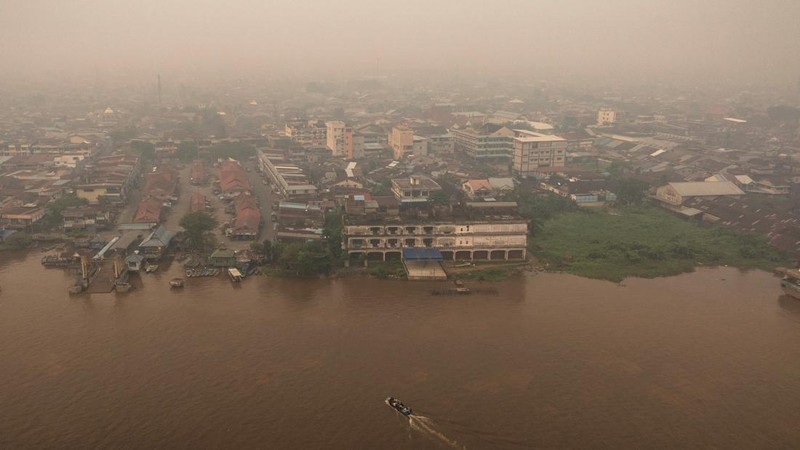 Tampilan dari drone memperlihatkan orang-orang menaiki perahu kayu menyeberangi Sungai Kapuas saat kabut asap akibat kebakaran hutan menyelimuti wilayah tersebut di Pontianak, Provinsi Kalimantan Barat, Indonesia, pada 27 Agustus 2026.