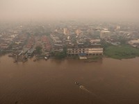 Tampilan dari drone memperlihatkan orang-orang menaiki perahu kayu menyeberangi Sungai Kapuas saat kabut asap akibat kebakaran hutan menyelimuti wilayah tersebut di Pontianak, Provinsi Kalimantan Barat, Indonesia, pada 27 Agustus 2026.(REUTERS/Willy