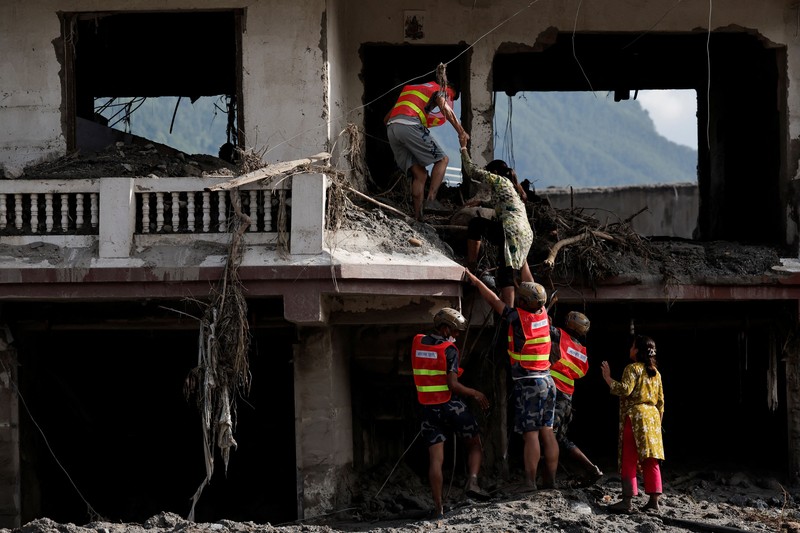 Warga melihat foto-foto korban tewas akibat banjir dan tanah longsor yang ditempel di gerbang untuk keperluan identifikasi di luar kamar jenazah di Kathmandu, Nepal, pada 27 Agustus 2026. (REUTERS/Sabrina Dangol)