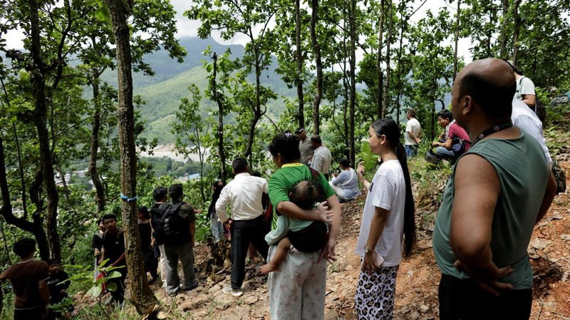 Warga berdiri di atas bukit setelah mencapai dataran tinggi menyusul peringatan bahwa tanggul danau telah jebol, dua hari setelah banjir bandang dan tanah longsor di Trishuli, distrik Nuwakot, Nepal, pada 28 Agustus 2026.