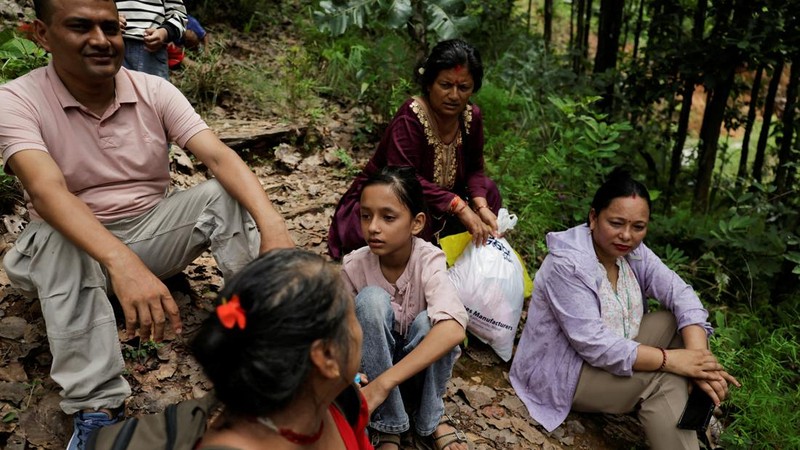 Warga duduk di atas bukit setelah mencapai dataran tinggi menyusul peringatan bahwa tanggul danau telah jebol, dua hari setelah banjir bandang dan tanah longsor di Trishuli, distrik Nuwakot, Nepal, pada 28 Agustus 2026.