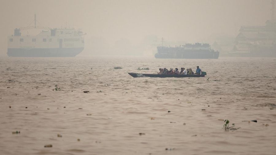 Warga menaiki perahu kayu melintasi Sungai Kapuas saat kabut asap akibat kebakaran hutan menyelimuti wilayah tersebut di Pontianak, Provinsi Kalimantan Barat, Indonesia, pada 27 Agustus 2026. (REUTERS/Willy Kurniawan)