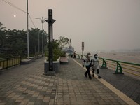 Warga yang mengenakan masker pelindung berjalan di tepi Sungai Kapuas saat kabut asap akibat kebakaran hutan menyelimuti kawasan tersebut di Pontianak, Provinsi Kalimantan Barat, Indonesia, pada 27 Agustus 2026.(REUTERS/Willy Kurniawan)