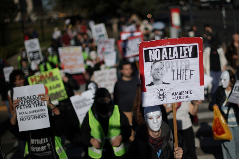 Para pengunjuk rasa membawa plakat dan boneka saat melakukan aksi long march di kediaman Peter Thiel&mdash;salah satu pendiri Palantir dan pemegang saham baru di Vista Energy&mdash;dengan seruan