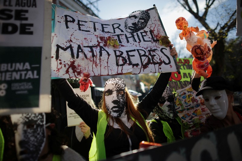 Para pengunjuk rasa membawa plakat dan boneka saat melakukan aksi long march di kediaman Peter Thiel&mdash;salah satu pendiri Palantir dan pemegang saham baru di Vista Energy&mdash;dengan seruan