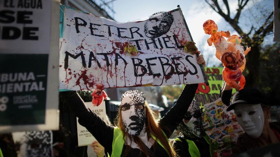 Para pengunjuk rasa membawa plakat dan boneka saat melakukan aksi long march di kediaman Peter Thiel—salah satu pendiri Palantir dan pemegang saham baru di Vista Energy—dengan seruan