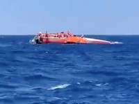 Para penumpang berdiri di atas kapal yang terbalik di lepas pantai Siprus Utara, 30 Agustus 2026, dalam gambar diam yang diambil dari sebuah video yang diperoleh Reuters. (FAIK GENCER/via REUTERS)