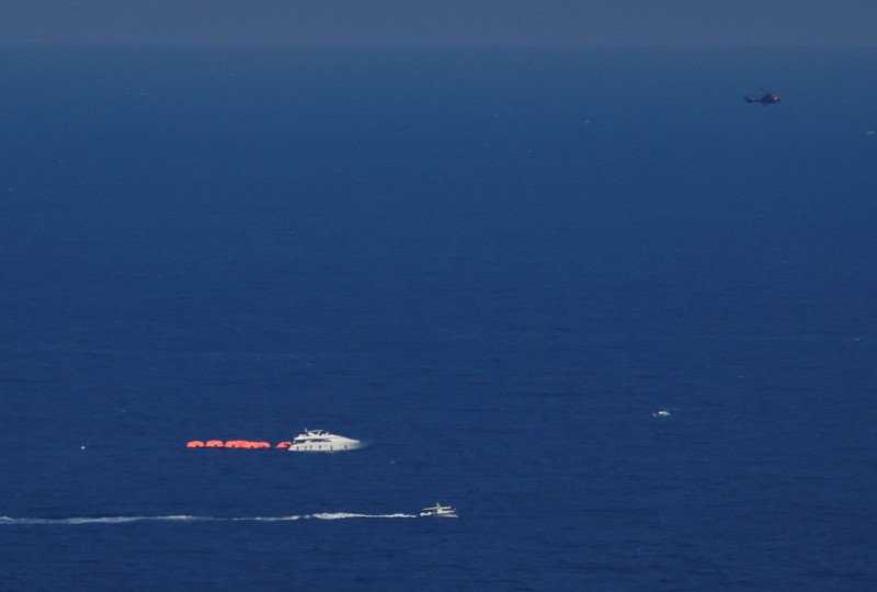 Para penumpang berdiri di atas kapal yang terbalik di lepas pantai Siprus Utara, 30 Agustus 2026, dalam gambar diam yang diambil dari sebuah video yang diperoleh Reuters. (FAIK GENCER/via REUTERS)