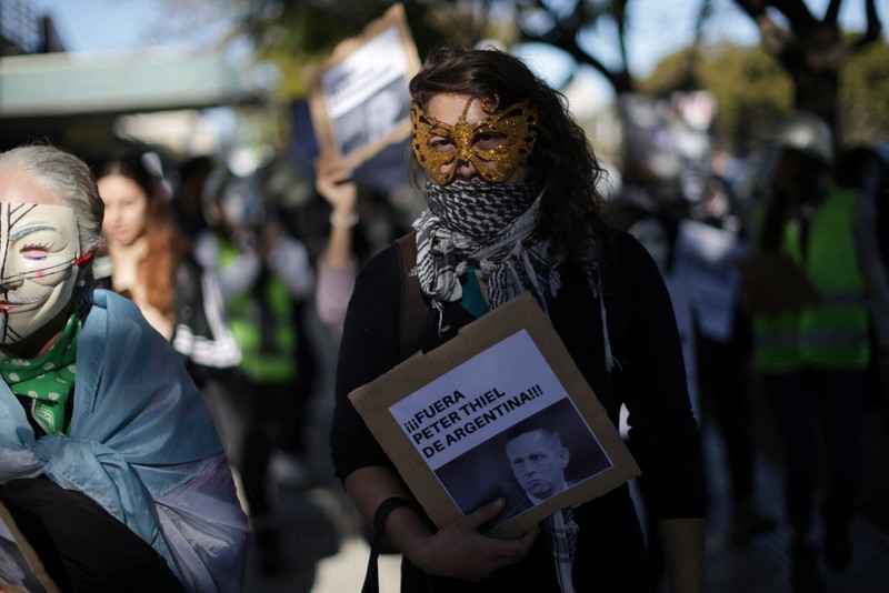 Para pengunjuk rasa membawa plakat dan boneka saat melakukan aksi long march di kediaman Peter Thiel&mdash;salah satu pendiri Palantir dan pemegang saham baru di Vista Energy&mdash;dengan seruan