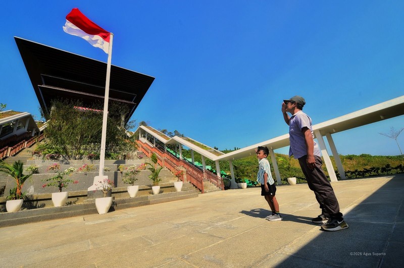 Seorang ayah dan anak putranya melakukan hormat kepada bendera di Istana Wakil Presiden Ibu Kota Nusantara, Penajam Paser, Kalimantan Timur. (Dok. Humas Otorita IKN/Agus Suparto)