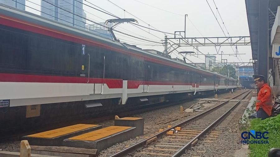 Seorang Petugas palang pintu perlintasan Kereta Api melihat Kereta Rel Listrik (KRL) Commuter Line melintasi di dekat Stasiun Karet, Jakarta, Selasa (1/9/2026). (CNBC Indonesia/Ferry Sandi)