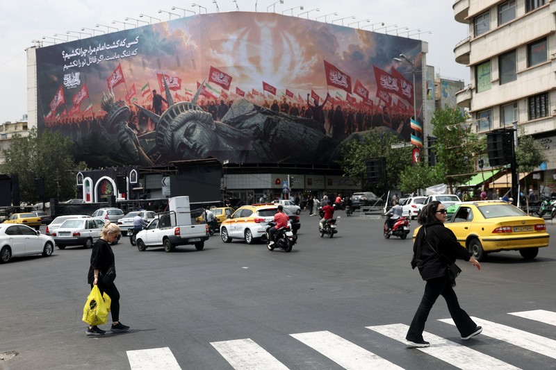 Warga berkendara di dekat papan reklame yang menampilkan Presiden AS Donald Trump pada sebuah gedung di Teheran, Iran, Senin (31/8/2026). (Majid Asgaripour/WANA via REUTERS)