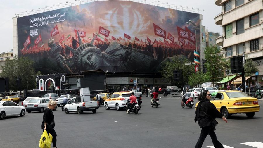 Orang-orang berjalan melewati papan reklame anti-AS di sebuah jalan di Teheran, Iran, Senin (3/8/2026). ((Majid Asgaripour/WANA via REUTERS))