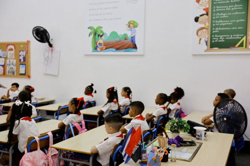 Para orang tua berjalan bersama anak-anak mereka di jalanan saat para siswa mengikuti hari pertama tahun ajaran 2026-2027 di tengah krisis ekonomi parah yang mendorong pihak berwenang untuk memberikan kelonggaran terkait jadwal, kehadiran, dan ketentuan seragam sekolah, di Havana, Kuba, 1 September 2026. (REUTERS/Norlys Perez)