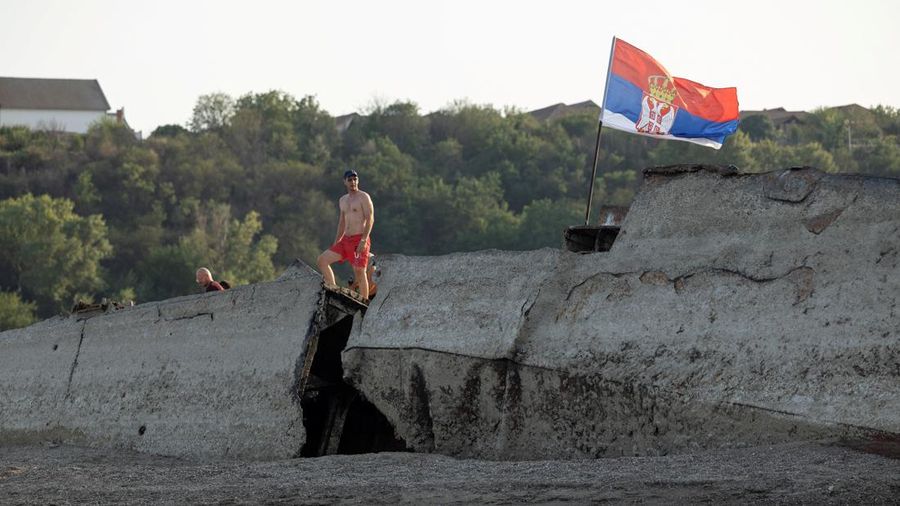 Seorang pria berdiri di atas kapal perang Jerman dari Perang Dunia II yang tenggelam dan kini muncul ke permukaan akibat surutnya air Sungai Danube—yang disebabkan oleh kekeringan dan suhu panas ekstrem—di dekat Prahovo, Serbia, pada 13 Agustus 2026.