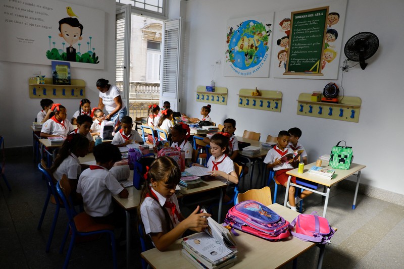 Para orang tua berjalan bersama anak-anak mereka di jalanan saat para siswa mengikuti hari pertama tahun ajaran 2026-2027 di tengah krisis ekonomi parah yang mendorong pihak berwenang untuk memberikan kelonggaran terkait jadwal, kehadiran, dan ketentuan seragam sekolah, di Havana, Kuba, 1 September 2026. (REUTERS/Norlys Perez)