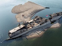 Tampilan dari drone yang memperlihatkan orang-orang berjalan di dekat bangkai kapal perang Jerman dari Perang Dunia II yang muncul ke permukaan akibat surutnya air Sungai Danube yang disebabkan oleh kekeringan dan suhu panas ekstremdi dekat Prahovo,