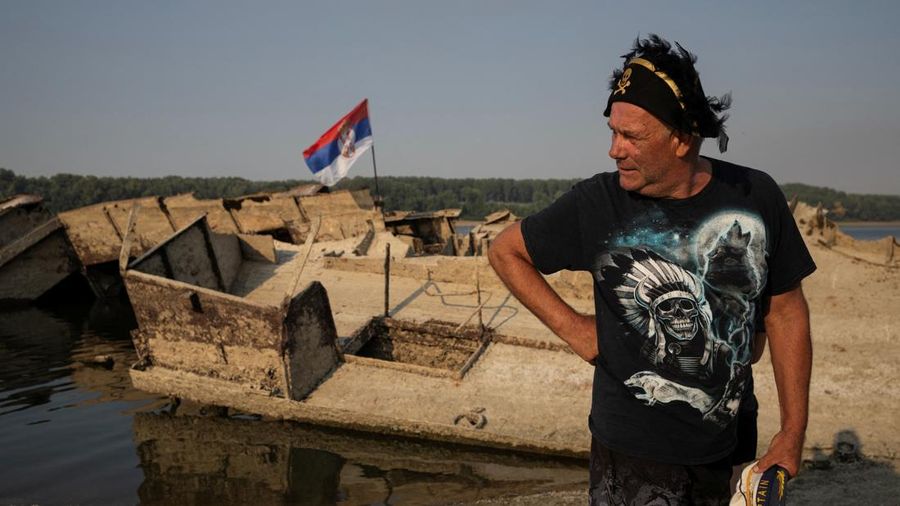 Zoran Lovric, seorang nelayan setempat, berdiri di dekat bangkai kapal perang Jerman dari Perang Dunia II yang muncul ke permukaan akibat surutnya air Sungai Danube—yang disebabkan oleh kekeringan dan suhu panas ekstrem—di dekat Prahovo, Serbia, pada 13 Agustus 2026.
