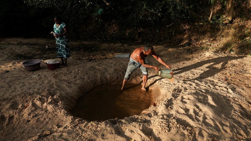 A.M. Pathmasena, 48 tahun, menggali lubang di dasar sungai yang mengering dan membersihkan air di dalamnya sebelum mandi, di Desa Galwela Yaya, Distrik Ampara, Sri Lanka, pada 27 Agustus 2026.