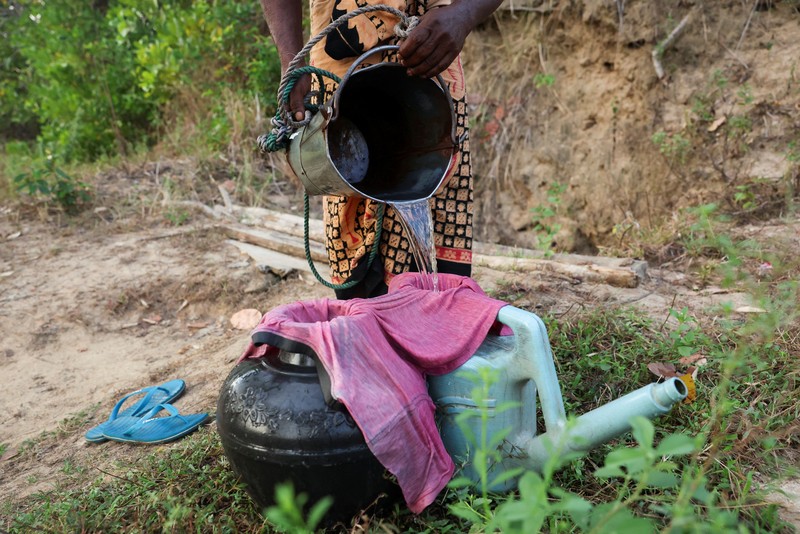 T.B. Leelawathie (49 tahun) dan temannya berjalan membawa ember dan bak saat hendak mandi di sungai yang telah mengering di Desa Galwela Yaya, Distrik Ampara, Sri Lanka, pada 27 Agustus 2026. (REUTERS/Priyanshu Singh)