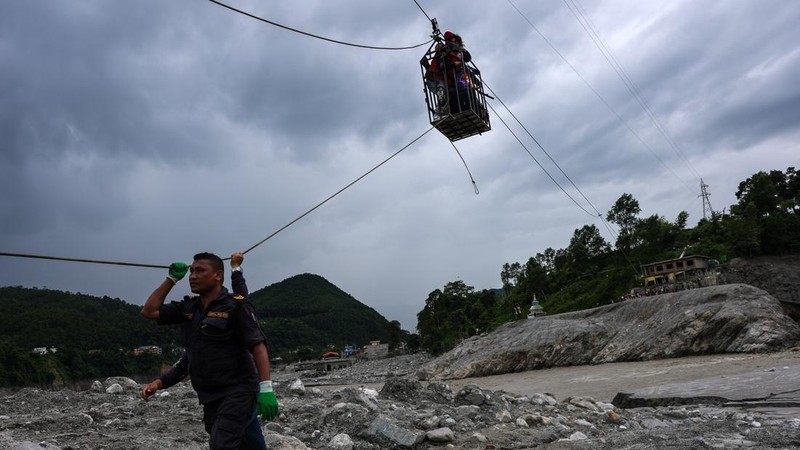 Sejumlah orang berada di dalam keranjang yang digantung pada tali luncur (zip line) darurat saat menyeberangi Sungai Trishuli dari Koloni, menyusul banjir bandang mematikan yang merusak jembatan dan sempat membuat warga terisolasi, di distrik Nuwakot