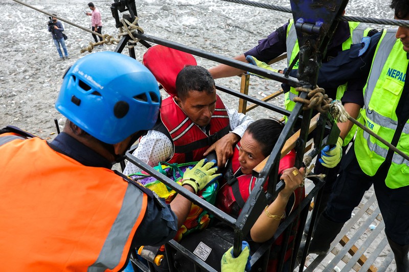 Sejumlah orang berada di dalam keranjang yang digantung pada tali luncur (zip line) darurat saat menyeberangi Sungai Trishuli dari Koloni, menyusul banjir bandang mematikan yang merusak jembatan dan sempat membuat warga terisolasi, di distrik Nuwakot, Nepal, pada 3 September 2026. (REUTERS/Athit Perawongmetha)