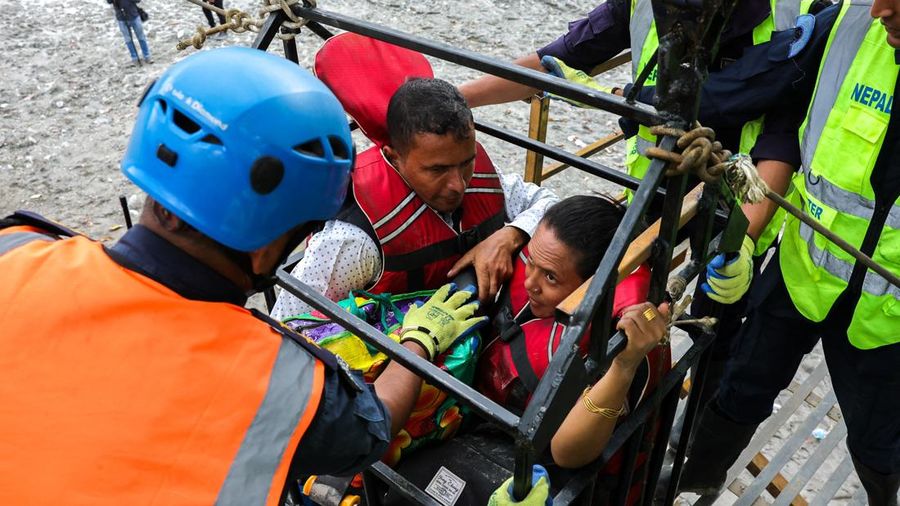 Sejumlah orang berada di dalam keranjang yang digantung pada tali luncur (zip line) darurat saat menyeberangi Sungai Trishuli dari Koloni, menyusul banjir bandang mematikan yang merusak jembatan dan sempat membuat warga terisolasi, di distrik Nuwakot, Nepal, pada 3 September 2026.