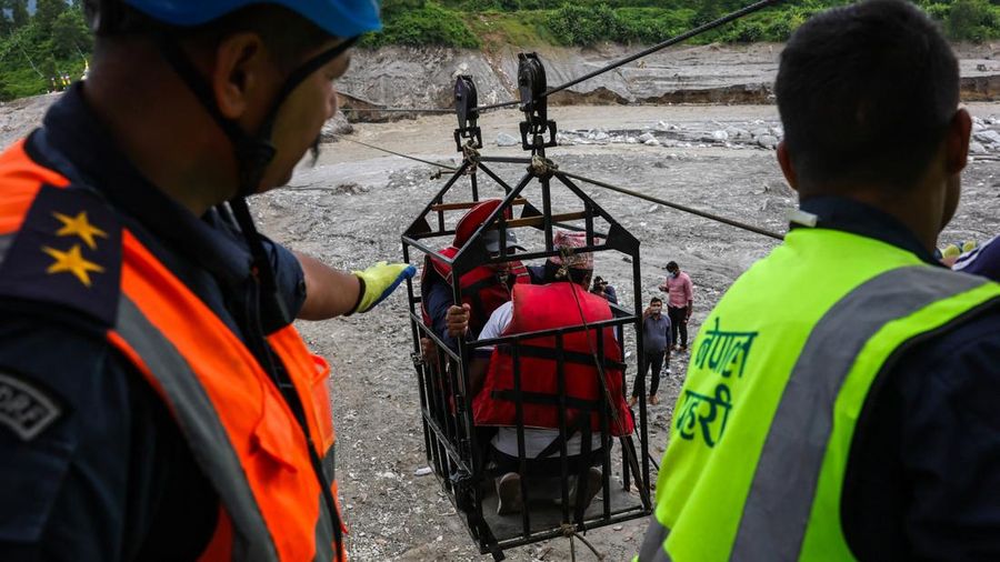 Sejumlah orang berada di dalam keranjang yang digantung pada tali luncur (zip line) darurat saat menyeberangi Sungai Trishuli dari Koloni, menyusul banjir bandang mematikan yang merusak jembatan dan sempat membuat warga terisolasi, di distrik Nuwakot, Nepal, pada 3 September 2026.
