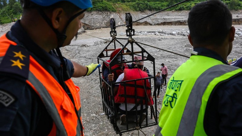 Sejumlah orang berada di dalam keranjang yang digantung pada tali luncur (zip line) darurat saat menyeberangi Sungai Trishuli dari Koloni, menyusul banjir bandang mematikan yang merusak jembatan dan sempat membuat warga terisolasi, di distrik Nuwakot, Nepal, pada 3 September 2026.