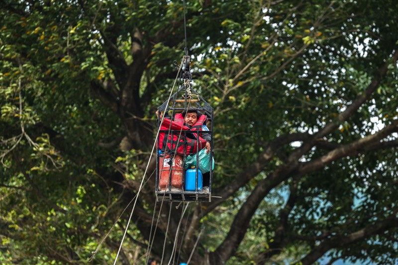 Sejumlah orang berada di dalam keranjang yang digantung pada tali luncur (zip line) darurat saat menyeberangi Sungai Trishuli dari Koloni, menyusul banjir bandang mematikan yang merusak jembatan dan sempat membuat warga terisolasi, di distrik Nuwakot, Nepal, pada 3 September 2026. (REUTERS/Athit Perawongmetha)