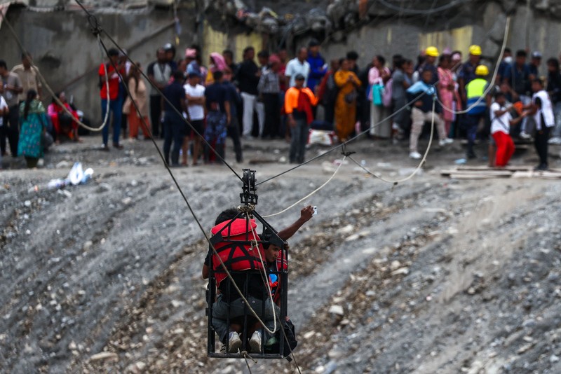Sejumlah orang berada di dalam keranjang yang digantung pada tali luncur (zip line) darurat saat menyeberangi Sungai Trishuli dari Koloni, menyusul banjir bandang mematikan yang merusak jembatan dan sempat membuat warga terisolasi, di distrik Nuwakot, Nepal, pada 3 September 2026. (REUTERS/Athit Perawongmetha)