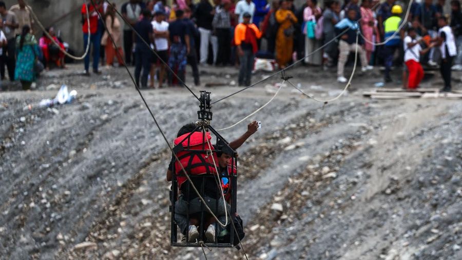Seorang pria berswafoto saat berada di dalam keranjang gantung pada jalur *zip-line* darurat ketika menyeberangi Sungai Trishuli dari Koloni—menyusul banjir bandang mematikan yang merusak jembatan dan sempat membuat warga terisolasi—di distrik Nuwakot, Nepal, pada 3 September 2026.