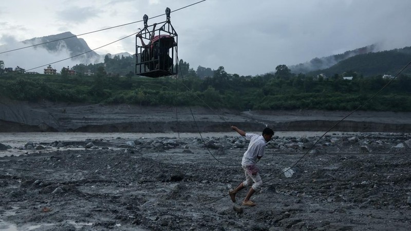 Seorang pria menarik tali luncur darurat yang membawa orang-orang menyeberangi Sungai Trishuli dari arah Koloni, setelah tanah longsor dan aliran lumpur merusak jembatan serta menyebabkan warga sempat terjebak di Trishuli, Distrik Nuwakot, Nepal, pada 2 September 2026.