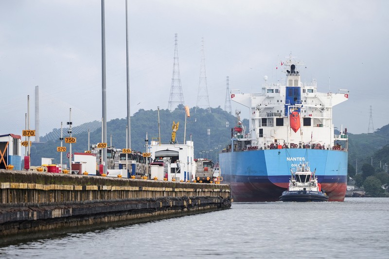 Para nelayan dari pelabuhan La Boca memuat tangki bensin ke atas perahu saat kapal berbendera Liberia, MSC ILLINOIS VII, melintasi Terusan Panama di tengah penurunan permukaan air akibat kurangnya curah hujan yang terkait dengan El Ni&ntilde;o, di Panama City, Panama, pada 4 September 2026. (REUTERS/Enea Lebrun)