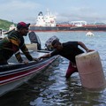 Para nelayan dari pelabuhan La Boca memuat tangki bensin ke atas perahu saat kapal berbendera Liberia, MSC ILLINOIS VII, melintasi Terusan Panama di tengah penurunan permukaan air akibat kurangnya curah hujan yang terkait dengan El Nio, di Panama Cit