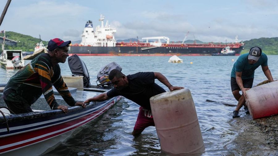 Para nelayan dari pelabuhan La Boca memuat tangki bensin ke atas perahu saat kapal berbendera Liberia, MSC ILLINOIS VII, melintasi Terusan Panama di tengah penurunan permukaan air akibat kurangnya curah hujan yang terkait dengan El Nio, di Panama Cit