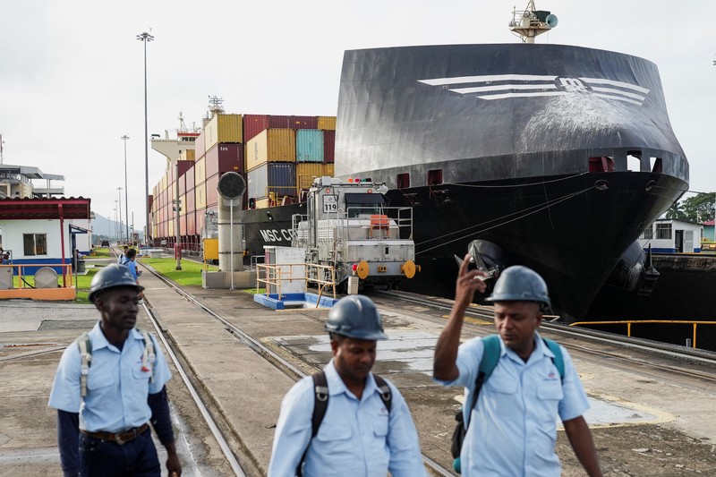 Para nelayan dari pelabuhan La Boca memuat tangki bensin ke atas perahu saat kapal berbendera Liberia, MSC ILLINOIS VII, melintasi Terusan Panama di tengah penurunan permukaan air akibat kurangnya curah hujan yang terkait dengan El Ni&ntilde;o, di Panama City, Panama, pada 4 September 2026. (REUTERS/Enea Lebrun)
