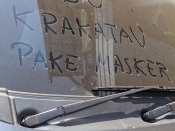 Sebuah mobil terlihat dengan tulisan Awas Debu Krakatau, Pakai Masker yang dibuat menggunakan debu vulkanik yang menempel pada kaca kendaraan akibat paparan erupsi Gunung Anak Krakatau. (Dok. Istimewa)