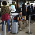 Seorang penumpang yang terlantar duduk di atas troli bagasi di area layanan pelanggan Bandara Internasional Soekarno-Hatta setelah bandara tersebut menghentikan operasionalnya akibat letusan Gunung Anak Krakatau, di Tangerang, dekat Jakarta, Indonesi